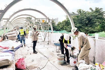 Công nhân thi công cầu bộ hành kết nối với các ga của tuyến Metro số 1 Bến Thành-Suối Tiên. 