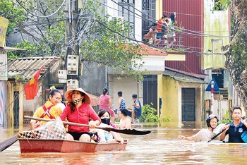 Người dân xã Yên Mỹ, huyện Thanh Trì, Hà Nội được hỗ trợ di chuyển đến nơi an toàn khi nước dâng cao. (Ảnh THẾ ÐẠI) 