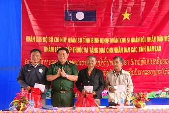 Đại tá Nguyễn Xuân Sơn, Phó Chính ủy Bộ Chỉ huy Quân sự tỉnh Bình Định tặng quà cho nhân dân ở cụm bản La Nhao, huyện Xá Mắc Khi Xay, tỉnh Attapu.