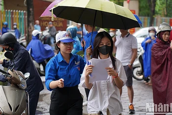 Tình nguyện viên "Tiếp sức mùa thi" năm 2023 hỗ trợ thí sinh dưới cơn mưa.