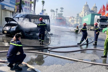Lực lượng chữa cháy nỗ lực dập tắt đám cháy xe ô-tô trên đường.
