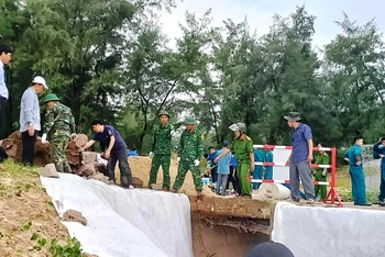Các cán bộ, chiến sĩ Biên phòng cùng lực lượng địa phương khắc phục sự cố sạt lở kè biển do mưa lũ ở xã Phú Diên (huyện Phú Vang).