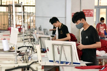 Công nhân Công ty cổ phần Nam Tiệp (Cụm công nghiệp An Xá, thành phố Nam Ðịnh, tỉnh Nam Ðịnh) may quần áo xuất khẩu. (Ảnh TRẦN HẢI)