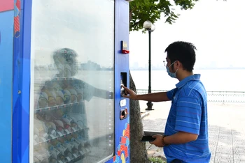 Người dân mua nước uống có đường tại máy bán nước tự động trên địa bàn thành phố Hà Nội. (Ảnh MỸ HÀ) 