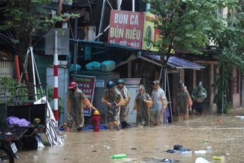 Người dân di chuyển đến nơi an toàn khi nước tại phố Chương Dương Độ (quận Hoàn Kiếm, Hà Nội) dâng cao. (Ảnh THẾ ĐẠI)