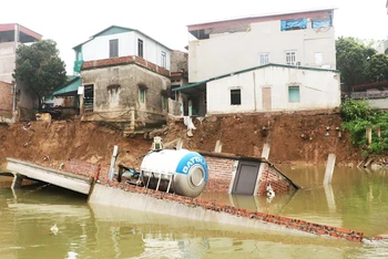 Sự cố sạt lở đê đã làm một ngôi nhà hai tầng trong khu vực trôi xuống sông.
