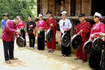 Nghệ nhân ưu tú Bùi Thanh Bình ( bên trái) hướng dẫn các em học sinh tìm hiểu và đánh Chiêng Mường, CLB Giữ gìn bản sắc văn hóa dân tộc Mường, trường THPT Quyết Thắng, Lạc Sơn – Hòa Bình.