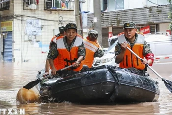 Cảnh sát Trung Quốc giúp sơ tán người dân khỏi các khu vực ngập lụt. (Ảnh: AFP/TTXVN)