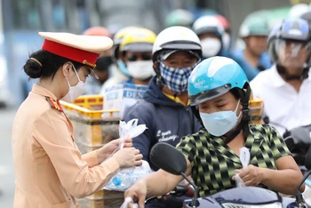 Nữ Cảnh sát giao thông phát nước suối cho người đi xe máy.