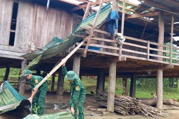 Cán bộ, chiến sĩ Đồn Biên phòng Ra Mai giúp bà con lợp lại nhà bị lốc xoáy làm hư hỏng.
