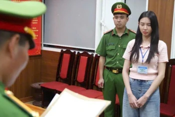 Hoa hậu Nguyễn Thúc Thùy Tiên nghe đọc lệnh từ cơ quan công an. (Ảnh: Bộ Công an)