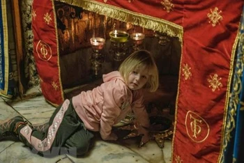 Một du khách nhỏ tuổi thăm hang đá, nơi tương truyền Chúa Jesus được sinh ra. (Ảnh: Quang Minh/TTXVN)