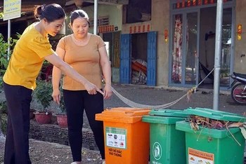 Cán bộ Hội Liên hiệp Phụ nữ xã Lang Minh, huyện Xuân Lộc, tỉnh Đồng Nai hướng dẫn người dân phân loại rác tại nguồn. (Ảnh MẠNH THÌN)