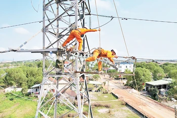 Công nhân Công ty Điện lực Quảng Bình đội nắng thi công đường dây điện 100kV.