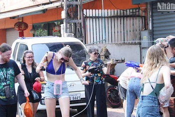 Du khách quốc tế thích thú trải nghiệm té nước trong dịp Bun Pi May năm 2023 của Lào. Ảnh: Trịnh Dũng