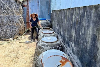 Bà Lý Thị Xuyên bơm nước dưới ao chứa vào lu, xử lý lại bằng phèn chua để có nước tắm, giặt.