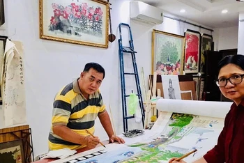 Hai họa sĩ người dân tộc Hoa Trịnh Chiêu Thành và Đào Kim Loan bên tác phẩm của mình.
