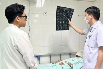 Bác sĩ thăm khám cho người bệnh sau phẫu thuật.