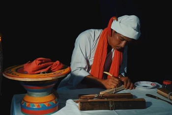 Phó Cả sư Nại Cao Liêm đang thực hiện công đoạn khắc chữ trên lá buông. (Ảnh: NGỌC XIÊM)