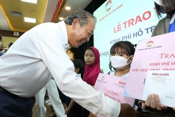 Đồng chí Trương Hoà Bình trao học bổng cho các em học sinh. (Ảnh: Hoàng Triều)