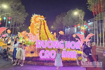 Du khách rất thích thú ngắm và chụp ảnh bên linh vật rồng, ngay đầu đường hoa. Ảnh: HỮU NGHĨA