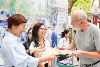Du khách người nước ngoài trân trọng khi đón nhận tờ phụ san đặc biệt của Báo Nhân Dân.