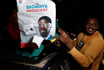 Người ủng hộ ông Bassirou Diomaye Faye mang theo poster chân dung ông. (Ảnh: Reuters)