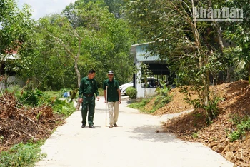 Hai cha con ông Bùi Văn Tượng đi trên con đường mới từ một phần đất gia đình đóng góp.