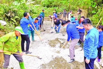 Cán bộ, hội viên các tổ chức giúp nhân dân thôn Bản Lằn trộn bê-tông làm đường giao thông thôn, bản.