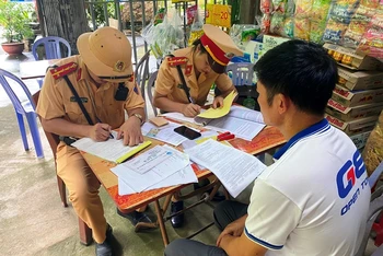 Cảnh sát giao thông Lào Cai lập biên bản xử phạt và tước giấy phép lái xe đối với tài xế và chủ doanh nghiệp "đội lốt" xe khách tuyến cố định. (Ảnh: QUỲNH TRANG)