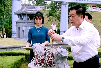 Trưởng Ban Tuyên giáo Trung ương Nguyễn Trọng Nghĩa thắp hương phần mộ các chiến sĩ tại khu lăng mộ. (Ảnh: Báo Yên Bái)