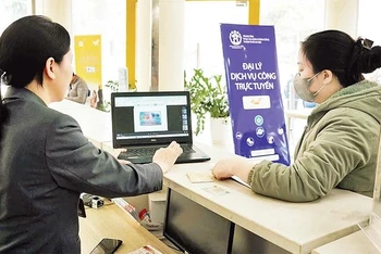 Người dân được nhân viên hướng dẫn làm thủ tục hành chính tại các đại lý dịch vụ công trực tuyến của thành phố Hà Nội.