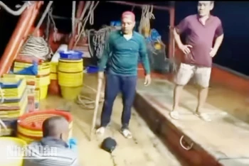 Thanh niên dùng cây gỗ đội nón màu cam đánh người trên tàu. (Ảnh cắt từ clip).