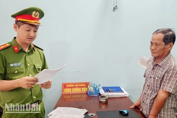 Điều tra viên đọc lệnh bắt tạm giam ông Trần Thiện Thi. (Ảnh: Văn Vũ)