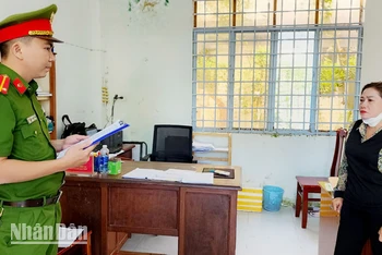 Cán bộ điều tra tống đạt quyết định khởi tố bị can đối với Võ Thị Thanh Nga. (Ảnh: VĂN VŨ)