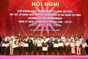 Bí thư Thành ủy Đinh Tiến Dũng và Bộ trưởng Lao động-Thương binh và Xã hội Đào Ngọc Dung trao bằng khen của Bộ Lao động-Thương binh và Xã hội cho người có công trên địa bàn thành phố Hà Nội.