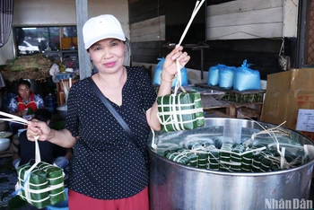 Cô Mai, người có thể gói 200 chiếc bánh chưng trong một buổi sáng, hào hứng khoe mẻ bánh đang được xếp vào nồi. (Ảnh: TRỊNH DŨNG)