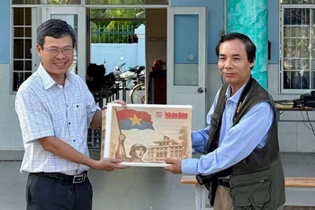 Nhà báo Trọng Duy, đại diện Văn phòng Báo Nhân Dân tại Bạc Liêu trao Phụ san đặc biệt của Báo Nhân Dân đến thầy giáo Dương Bình, Bí thư Chi bộ, Hiệu trưởng Trường Trung học phổ thông Chuyên Bạc Liêu.