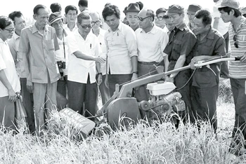 Tổng Bí thư Nguyễn Văn Linh xem máy cắt lúa trên đồng ruộng của HTX Phước Tú, huyện Bến Lức, tỉnh Long An (năm 1988). Ảnh | XUÂN LÂM