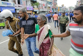 Người phụ nữ Sri Lanka nhận được sự giúp đỡ bên ngoài Đền thờ Thánh Anthony sau vụ nổ ngày 21-4. (Ảnh: AP)
