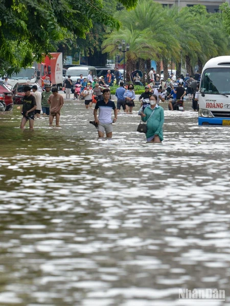 Sáng 24/7, nước ngập sâu khiến các phương tiện không thể đi qua, người dân buộc phải lội nước di chuyển ra ngoài.