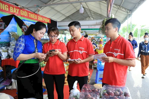 Nhân viên Viettel Sơn La hướng dẫn các hộ kinh doanh chợ Chiềng Đen (thành phố Sơn La) sử dụng Viettel Money. Ảnh: Luyện Ngọc Tuấn