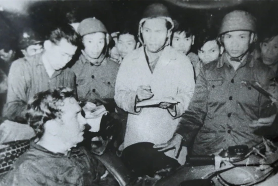 Nhà báo Phạm Thanh (người mặc áo khoác trắng) cùng nhà báo Đỗ Quảng (người đầu tiên, bên trái), phỏng vấn phi công lái máy bay B52 Mỹ bị bắt tại bãi đá Phương Liệt, Hà Nội đêm 25/12/1972. Ảnh: Bảo tàng Báo chí Việt Nam