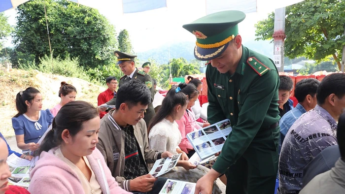 Cán bộ, chiến sĩ Bộ đội Biên phòng tỉnh Điện Biên phát tờ rơi tuyên truyền bảo vệ rừng đến nhân dân trên khu vực biên giới Việt-Lào.