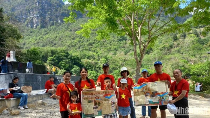Du khách mang theo phụ san của Báo Nhân Dân về Chiến dịch Hồ Chí Minh, check-in tại thác Bản Giốc, xã Đàm Thủy, huyện Trùng Khánh, tỉnh Cao Bằng.