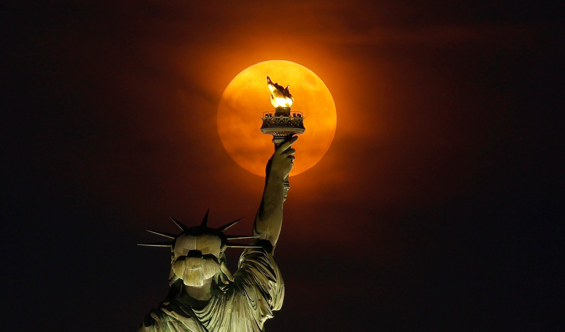 Siêu trăng mọc qua màn sương mù phía sau Tượng Nữ thần Tự do ở thành phố New York, Mỹ. (Ảnh: Getty Images)