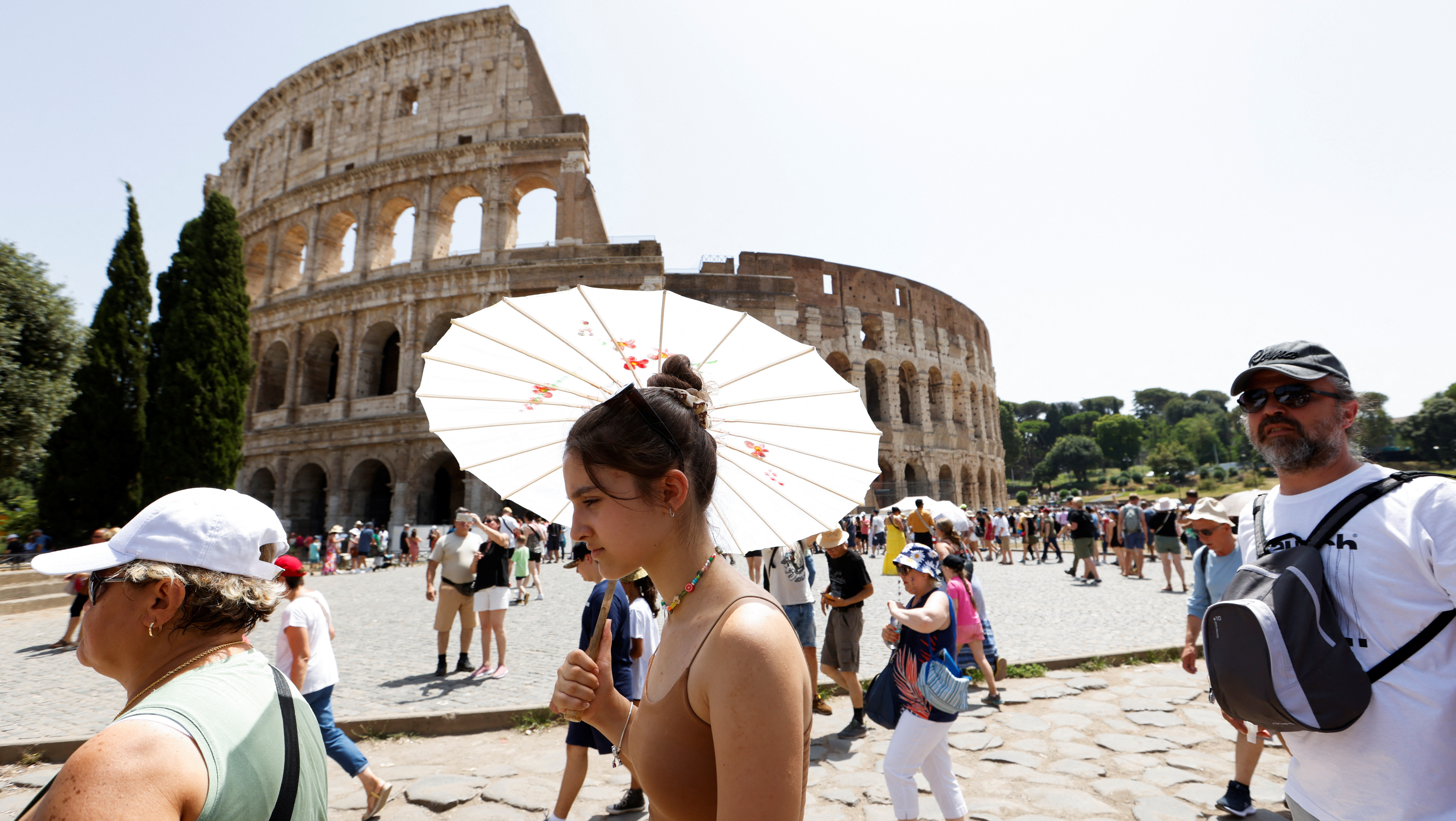 Khách du lịch đi bộ gần Đấu trường La Mã tại Rome trong đợt nắng nóng lan rộng khắp Italia, ngày 17/7/2023. (Ảnh: REUTERS)