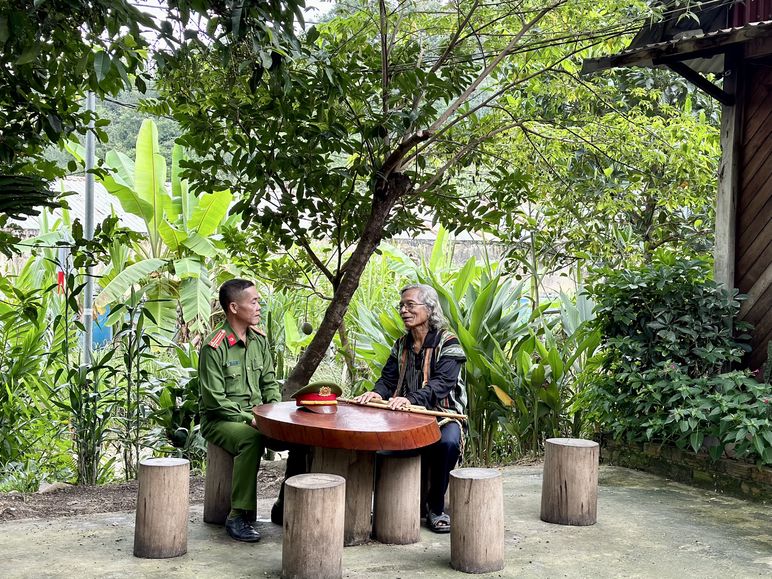 Trung tá Ating Chơn trao đổi với già làng Bríu Pố về công tác giữ gìn an ninh trật tự tại địa phương