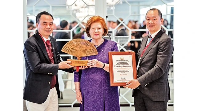 Doanh nhân Nguyễn Văn Tưởng (ngoài cùng bên trái) tặng bà Vaira Vike-Freiberga - Chủ tịch câu lạc bộ Madrid, cựu Tổng thống Litva chiếc quạt trầm hương.