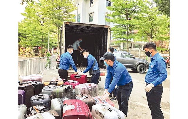 Đoàn viên, thanh niên tình nguyện thành phố giúp đỡ người dân vận chuyển hành lý về khu cách ly tập trung.